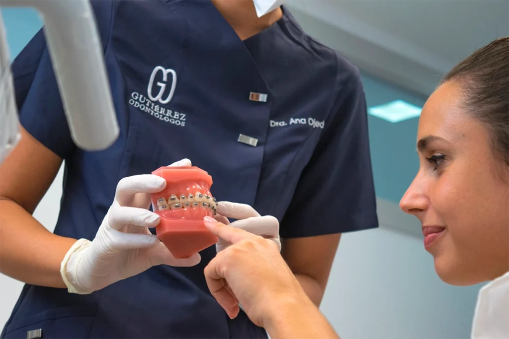 Dra. Ana Ojeda, ortodoncista en Almería, muestra a una paciente un modelo con brackets metálicos en la clínica dental Gutiérrez Odontólogos