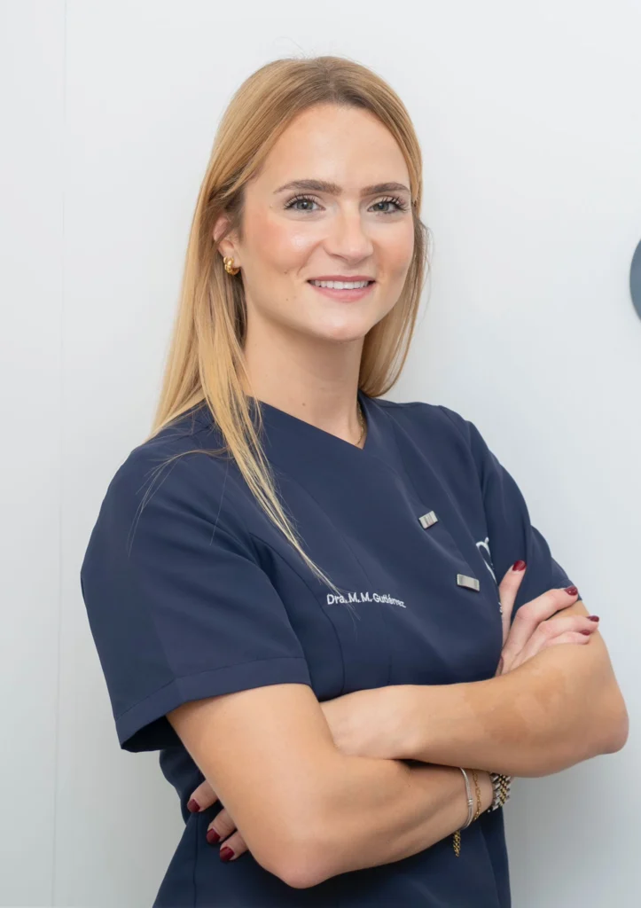 Dra. María del Mar Gutiérrez, dentista en Almería experta en periodoncia, implantología y armonización orofacial, posando en la clínica Gutiérrez Odontólogos con uniforme azul