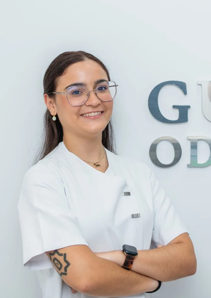 Enola Belmonte, higienista dental en la clínica Gutiérrez Odontólogos de Almería, posa con bata blanca junto al logotipo corporativo
