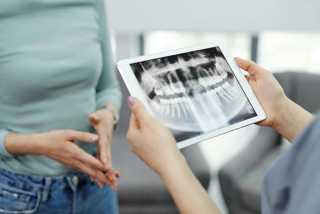 Dentista con reseñas en Almería muestra a una paciente una radiografía panorámica en tablet, resaltando la tecnología avanzada de la clínica dental Gutiérrez Odontólogos